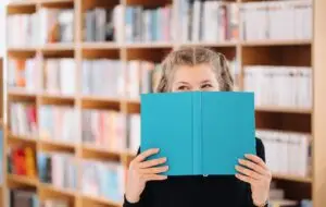 girl hiding face behind book